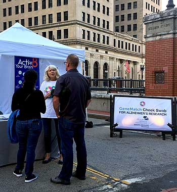 Dr. Karen Bell, a volunteer with the Memory and Aging Program at Butler Hospital, talks with people about Alzheimer's research at a September, 2018 Waterfire event in Providence, Rhode Island.